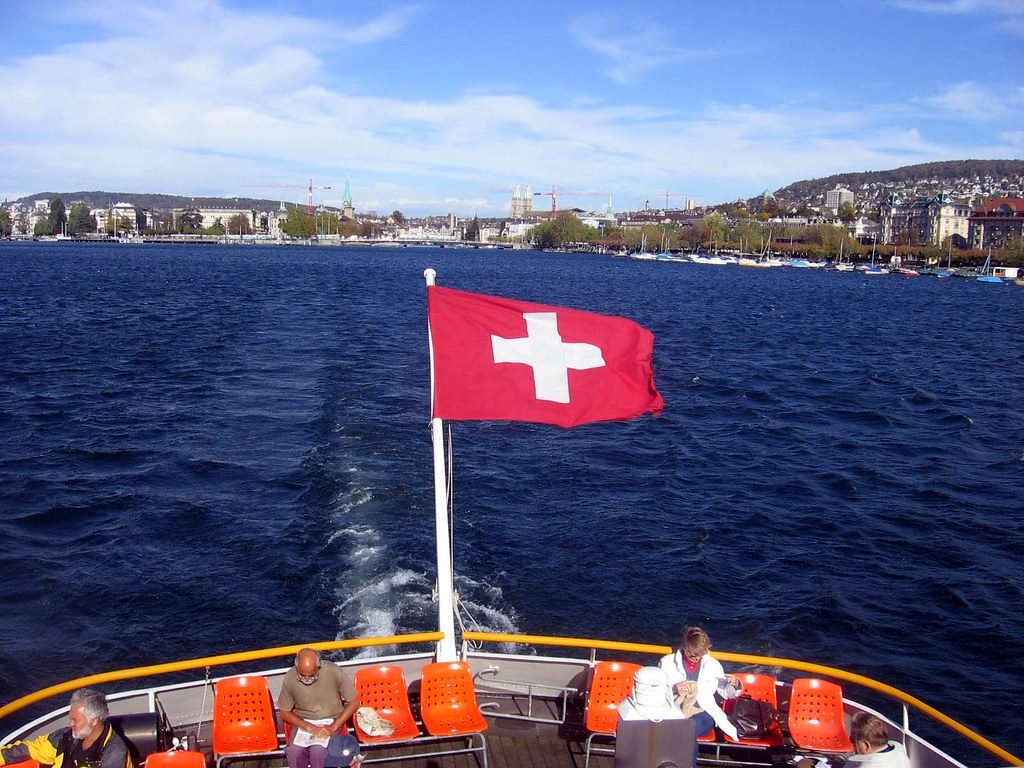Swiss flag over Lake Zurich with the city beyond
