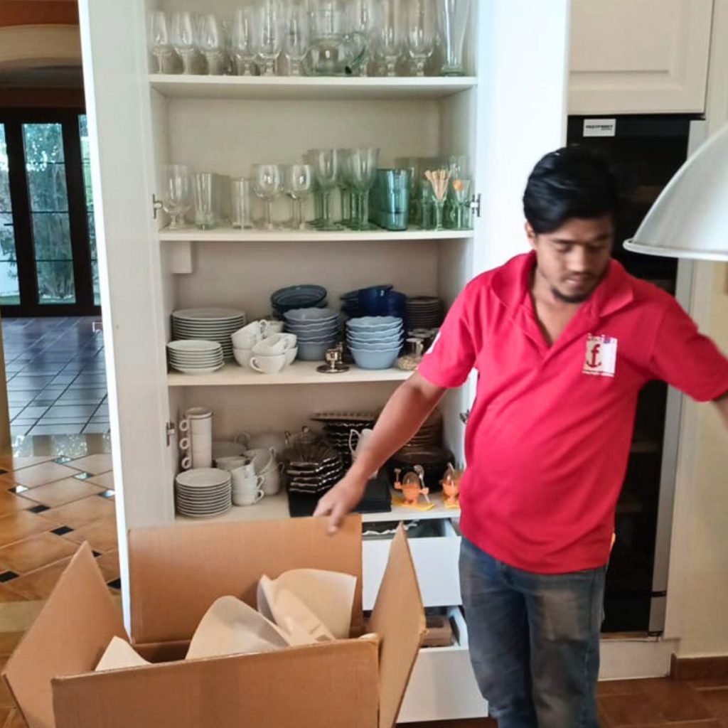 Fusion packer boxing glassware and china from a kitchen cabinet before an international move