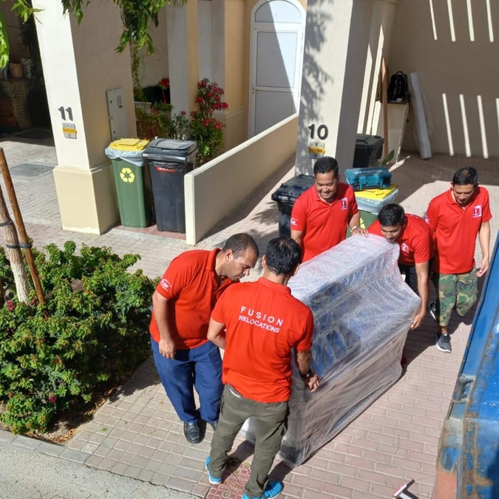 Fusion moving team carrying shrink-wrapped furniture between Dubai villas